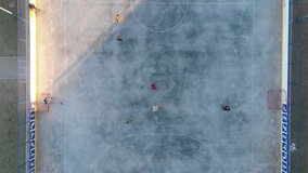 Children playing ice hockey outdoors in the city, aerial video. Skating ring, hockey field, drone flight. 