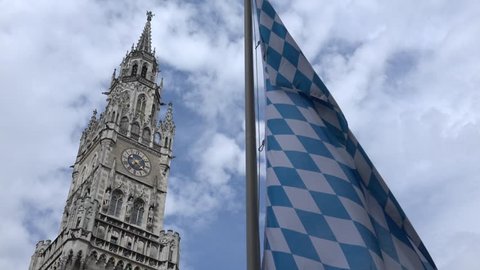 ULTRA HD 4K New town hall tower with public clock in Munich with local flag, landmark in sunny day