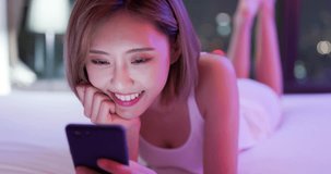 woman use smart phone happily and lying on the bed at night