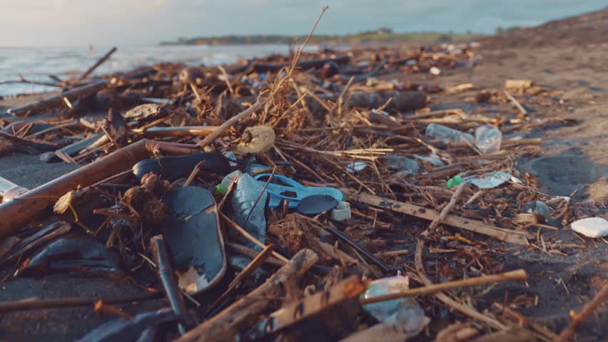 Plastic bottles, bags and other garbage dumped on dark sand of the beach and in ocean. Environmental pollution problem concept Royalty-Free Stock Footage #1019782684