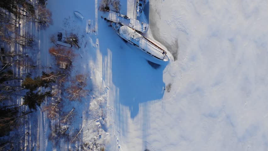 Aerial vertical shot of Frozen harbor and ships at sunset. Siberia
