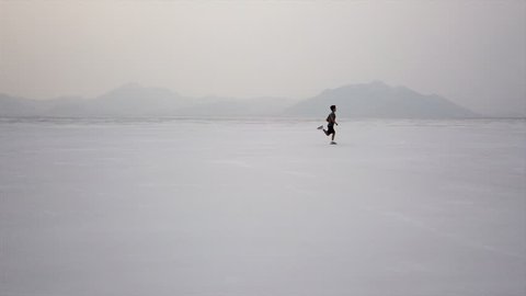 Dramatic aerial of boy running in desert Utah salt flat