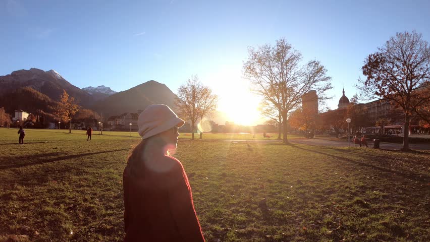 Travel Tourist Happy Asian women walking on field with beautiful view of sunset at Interlaken, Switzerland.