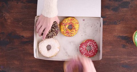 Top view of delicious sweet donuts. People take donuts out of the box on a wooden table background.