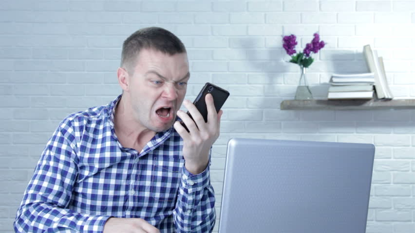 Portrait of an angry young businessman yelling at mobile phone while sitting at the table Royalty-Free Stock Footage #1019806585