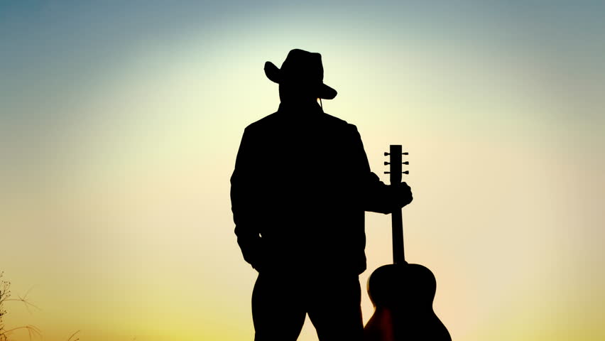 Cowboy man holding guitar at sunset  Royalty-Free Stock Footage #1019810134