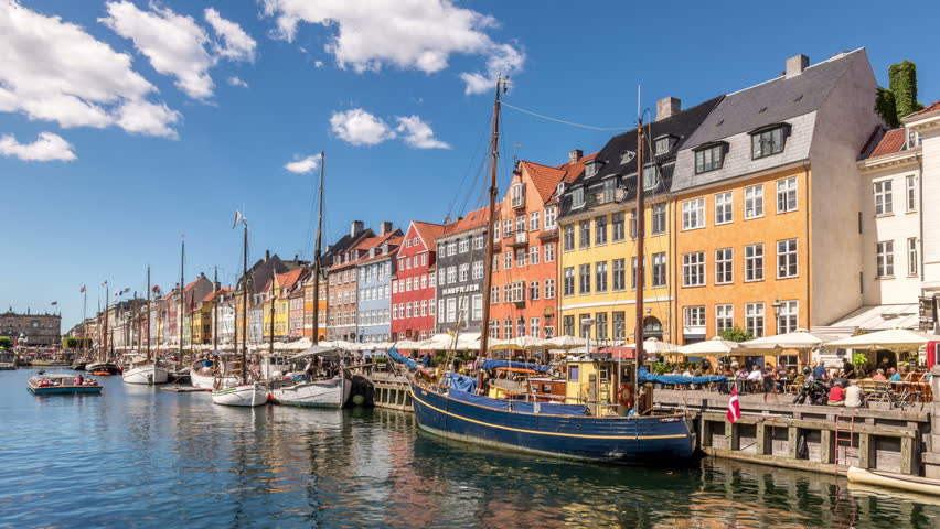 Nyhavn canal (New Harbour), a 17th-century waterfront and entertainment district in Copenhagen, Denmark. Colorful houses facades and sailing boats. White clouds move across blue sky. Time lapse video. Royalty-Free Stock Footage #1019812078