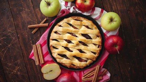 Homemade pastry apple pie with bakery products on dark rusty wooden kitchen table red and green apples and cinnamon. Traditional american dessert. Flat lay food background. Top view