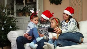 Adorable children laugh with mom and dad spending family time together on Christmas eve in decorated tree living room