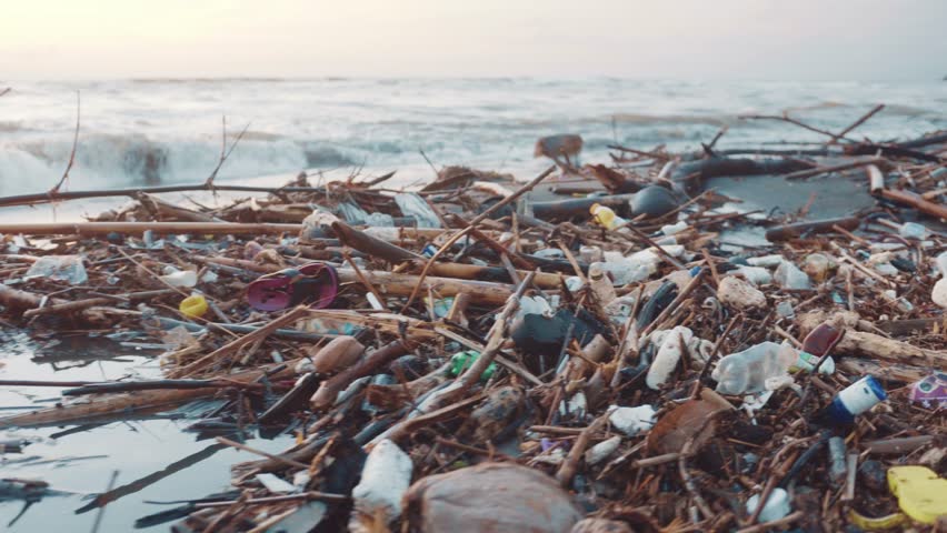 Plastic bottles, bags and other garbage dumped on dark sand of the beach and in ocean. Environmental pollution problem concept Royalty-Free Stock Footage #1019822176