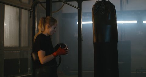 MS Caucasian female puts on boxing gloves in a boxing studio before training. 4K UHD