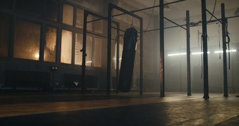 WS EST Boxing punching bag swinging in an old indoor boxing studio, no people. 4K UHD