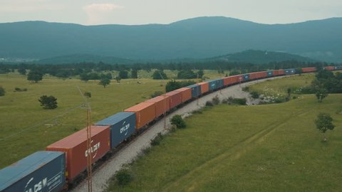 Aerial WS of a long freight train container composition on Mediterranean landscape. Slovenia, June 2015