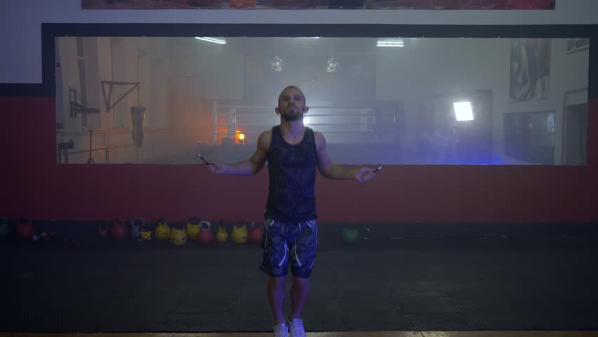 KHERSON, UKRAINE - OCTOBER 10, 2018: healthy young boxer man jumping rope on the background of a large mirror in a dark gym during training | Shutterstock HD Video #1019840716