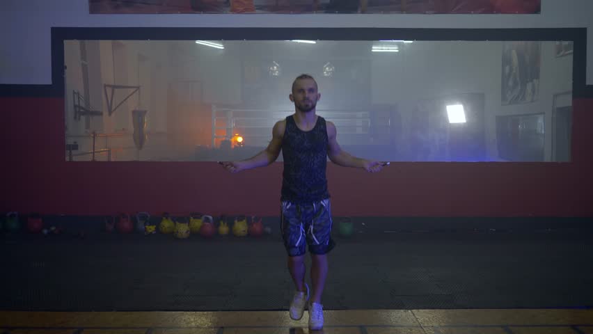 KHERSON, UKRAINE - OCTOBER 10, 2018: young healthy athlete man jumping rope on the background of a large mirror in a dark gym during training | Shutterstock HD Video #1019840752
