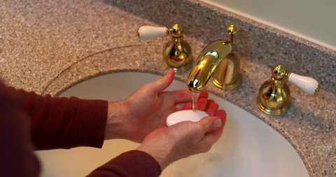 Man Washes Hands in Sink with Shiny Brass Faucet