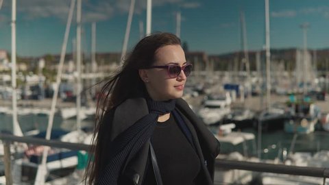Woman in sunglasses walking with a lot of yachts and boats behind. 4k shot
