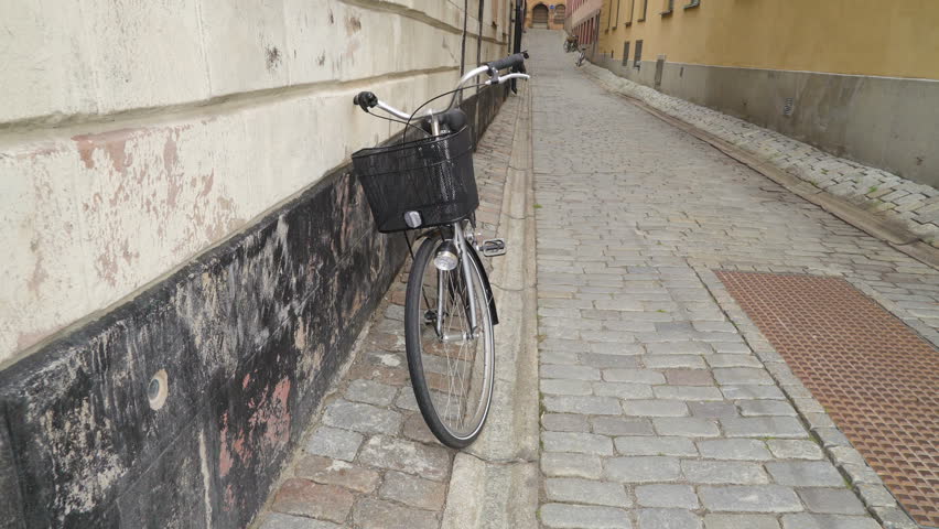The headlight on the front of the bicycle in Stockholm Sweden while being parked on the side of the wall of the building