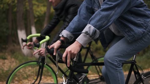 Young couple have fun riding on bikes in autumn park. Footage of rudders with hands. People, activity, leisure concept. Side view