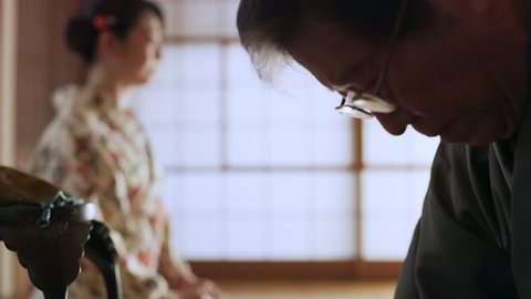 Man making tea with a cup of hot, steaming water and pouring it into a bowl in a traditional Japanese home with soft day lighting. Close up shot on 4k RED camera.
