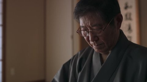 Elderly master preparing a bowl of tea during a historic tea ceremony in a traditional classic Japanese home with soft day lighting. Close up shot on 4k RED camera.
