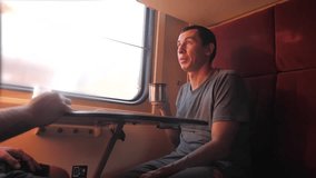 man is sitting on the train carriage holding a Railway and drinking coffee and tea. slow motion video. two men drinking tea on the train talking the train social media lifestyle. man with smartphones