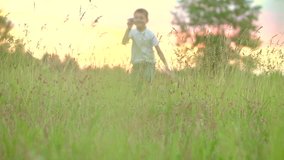 Happy Boy playing with paper airplane on the field over sunset background. Kid throws a paper plane, dream, freedom concept. Slow motion video footage 240 fps. Full HD 1080p. High speed camera 