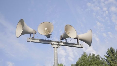 Loudspeaker warning system. System of alert for population. Sound amplifier with loudspeaker against the sky and fresh green forest.