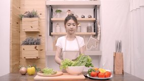 Blogger Asian woman using camera recording how to make salad healthy food video for her subscriber, female use organic vegetables preparing salad for fit body at home. Healthy food concept.