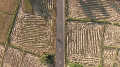 Aerial view Sidecar driving along empty countryside road rice field at sunset. Asia