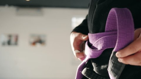 Karate purple belt tied around marital artists torso wearing black dojo GI's jiu jitsu mma fighter wearing gym ring