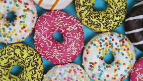 assorted donuts with different fillings and icing on a blue background. top view. Rotation video