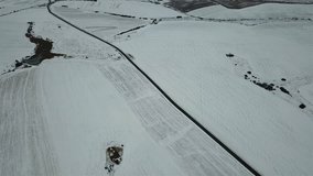 Aerial view of the winter road on the background of snow-covered fields. Top view from a drone