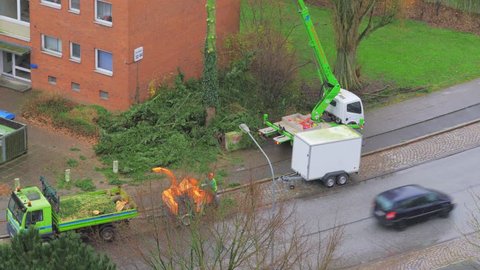 LUBECK, GERMANY - DECEMBER 08, 2017: City service workers using wood chipping machine after cutting trees on street. Lubeck. Germany