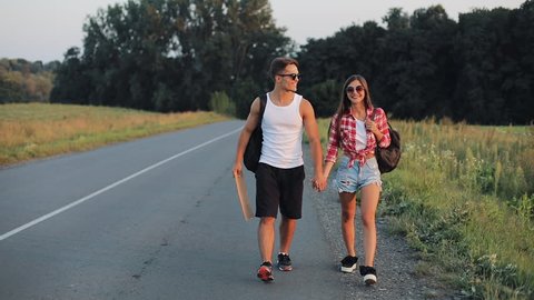 Couple On Vacation Hitchhiking Along Road and Holding Anywhere Sign. Summer time. Hitchhiking, tourists, adventures concept