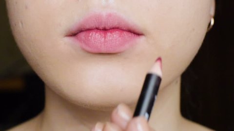 The girl does makeup on her lips. Applying red lipstick to lips. Close-up. HD 
