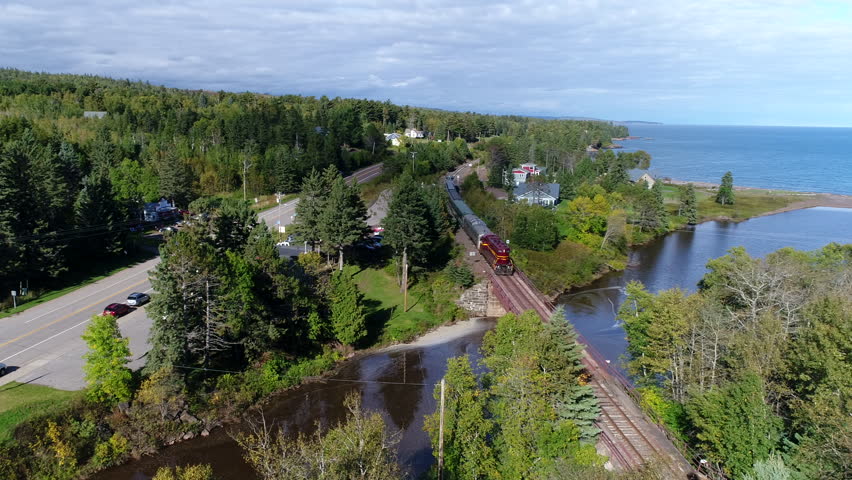 A passenger train moves down the tracks over a creek that flows into lake Superior on Minnesota