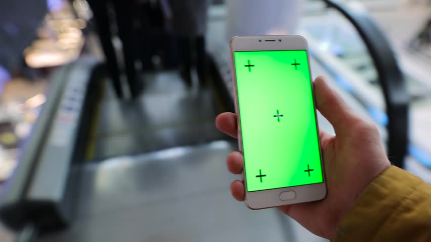 POV, male hand using smartphone with green screen chroma key in escalator of shopping mall