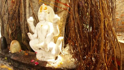 Marble statue of godess Ganga under big banyan tree near lingams hindu temple Rishikesh