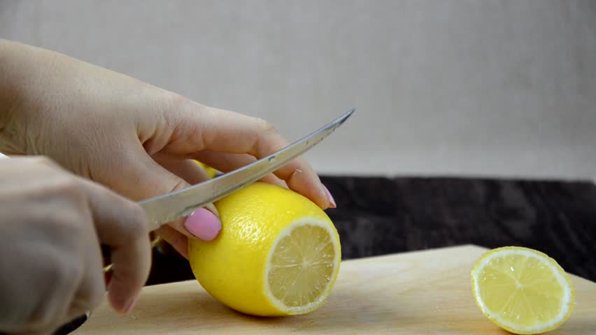 Closeup of hand with knife cutting lemon. to make a healthy drink. Teapot of ginger tea with honey and lemon on wooden table. tea with honey and lemon on wooden table Royalty-Free Stock Footage #1019920732