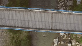 The aerial video shootage of the man riding a bike alongside the bridge.
