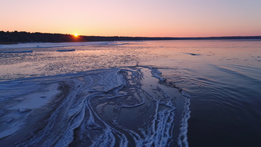 Frozen winter sea melting and ice floes drifting with waves aerial shot