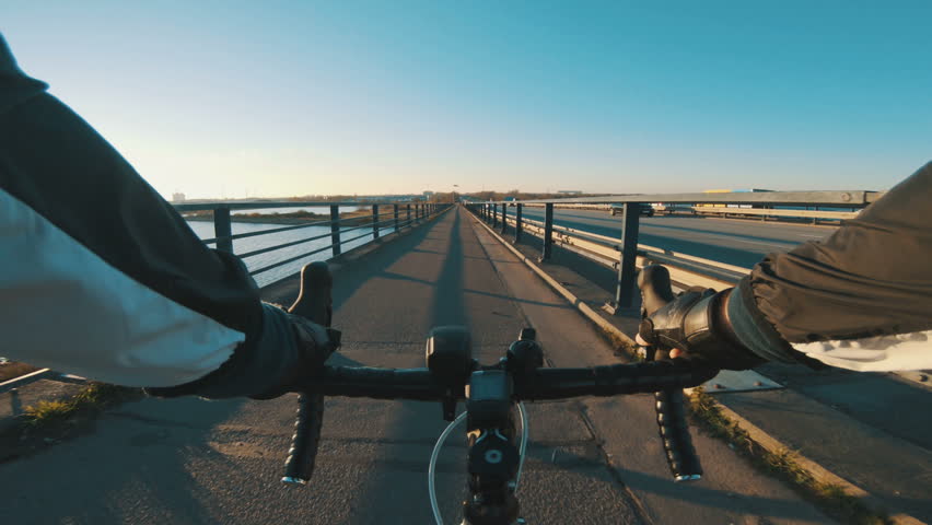 POV of racing bicycle crossing bridge next to cars