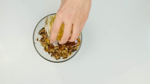 Woman adding honey to a nut butter and mixing ingredients in bowl. 4K