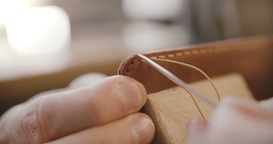 Macro close-up shot of leather sewing process details, hands with needle and strings making a bag on saddler in workshop Royalty-Free Stock Footage #1019938378