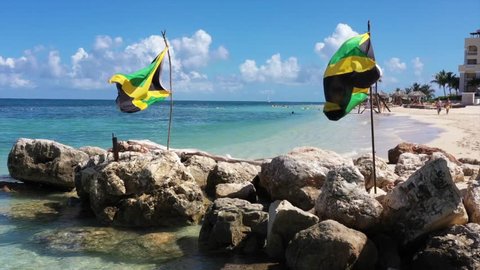 Aerial footage of jamaican flags on a beautiful tropical caribbean beach on Jamaica