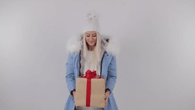Happy Amazed Woman in winter fur coat, Holding Present in Her Hands, makes a wish and gets a gift box. White background, 4k slow motion video