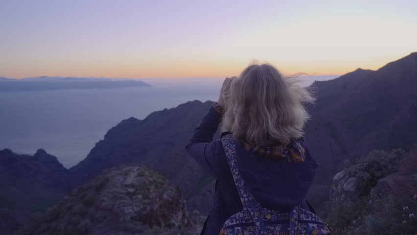 Mature woman in hiking adventures on a mountain top looking at the horizon through binoculars Royalty-Free Stock Footage #1019947357