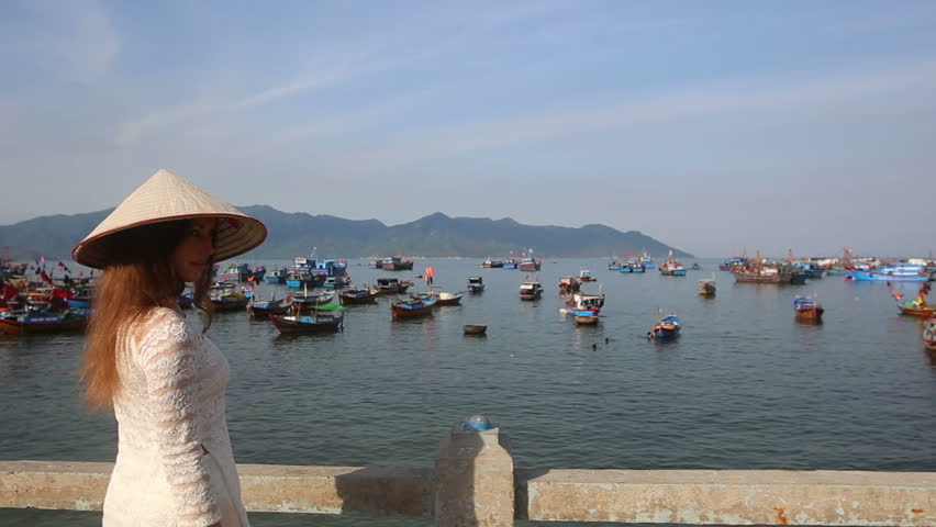 european blonde girl in vietnamese national costume amuse herself on embankment of fishing village
