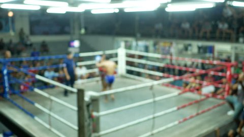 blurred decocus footage of asian men thai boxing are punch and kick together with committee on canvas boxing stadium

